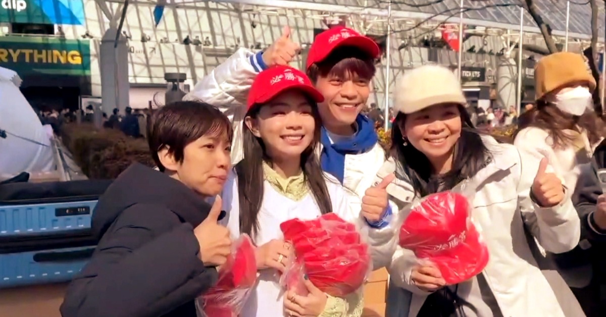 蔡阿嘎和二伯在東京巨蛋外頭，發放印有「必勝宮」字樣的紅色帽子。（圖／東森新聞）