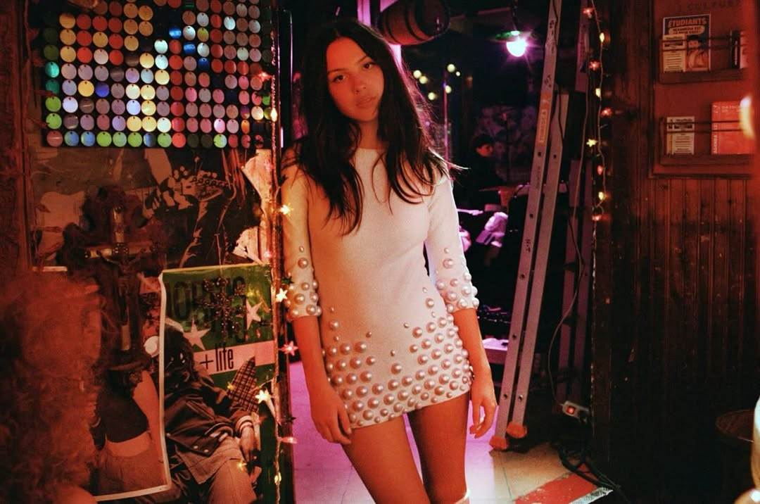 奧莉維亞（Olivia Rodrigo）在〈drop dead〉MV中穿著白色珍珠裙在酒吧漫舞。（圖／翻攝自Olivia Rodrigo &nbsp;IG）