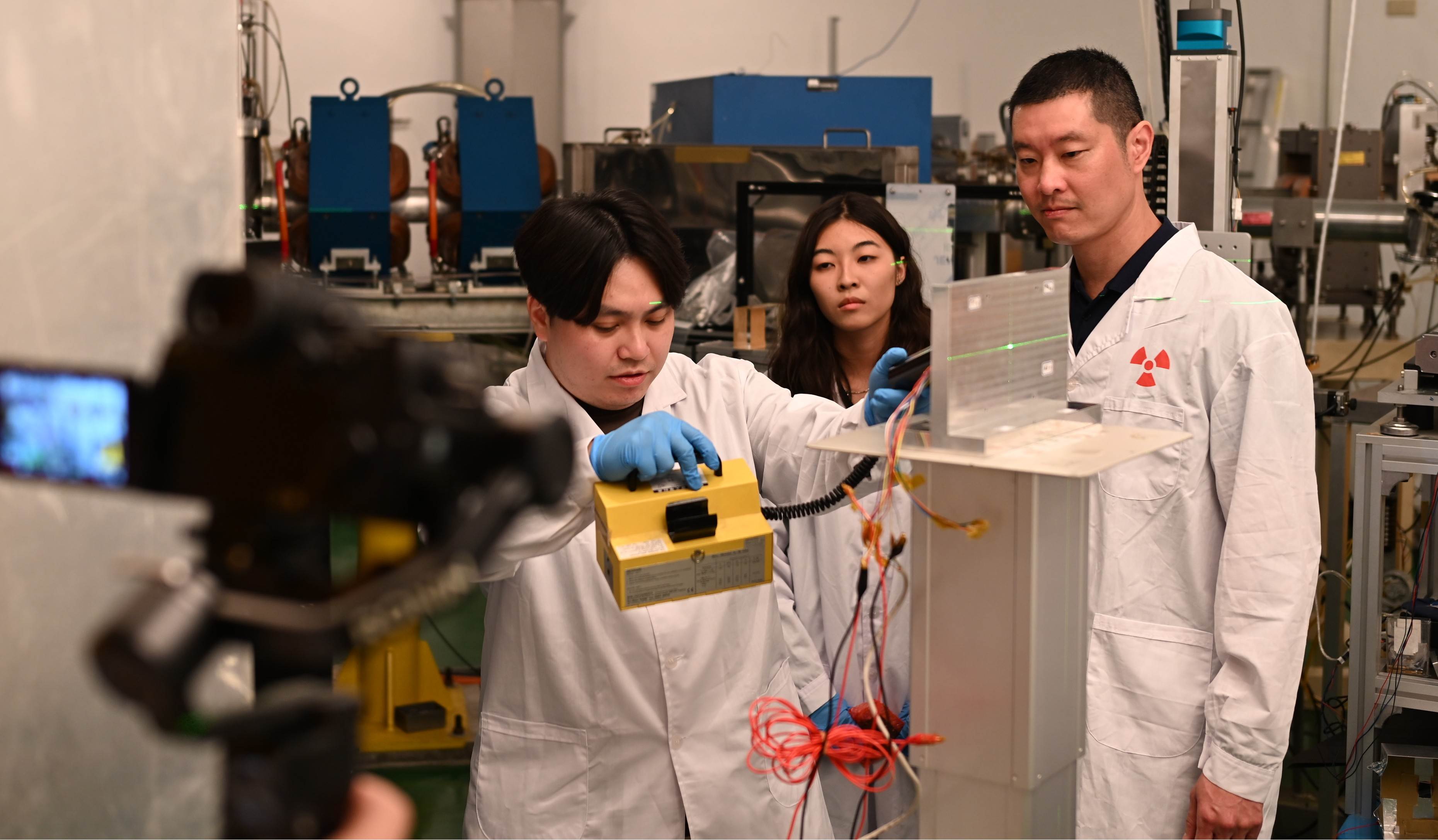 拍攝中央大學太空系主任張起維（右）率團隊在國原院模擬準備用質子加速器對深太空輻射探測儀進行輻射測試。（圖／台灣導演張皓然提供）