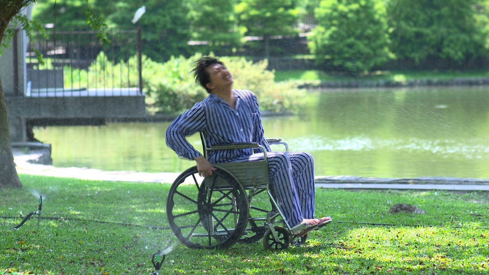 拍攝空檔吳皓昇苦中作樂，笑稱大家都在高溫下曝曬，只有自己能躲樹蔭「玩水消暑」。（圖／民視）