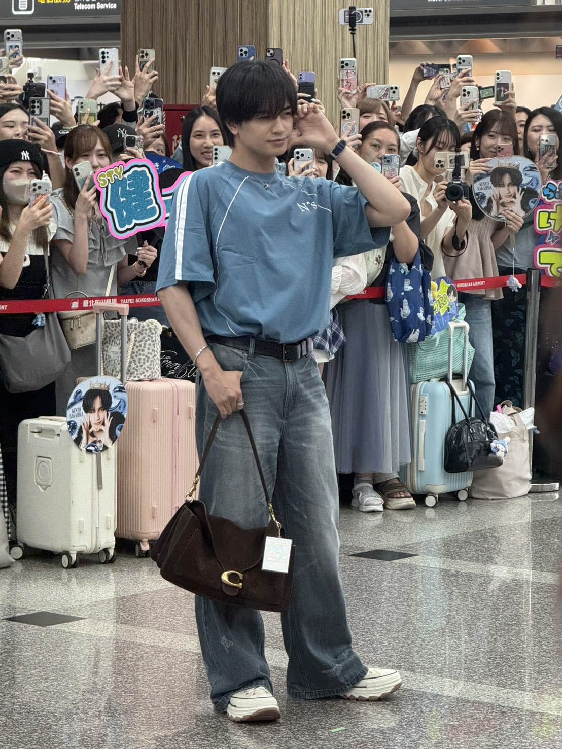 中島健人身穿背號13號寫著「Kento」的淺藍色球衣搭配牛仔褲現身機場,包上還掛著「青眼白龍」的小卡。(圖/記者楊雅芸攝)