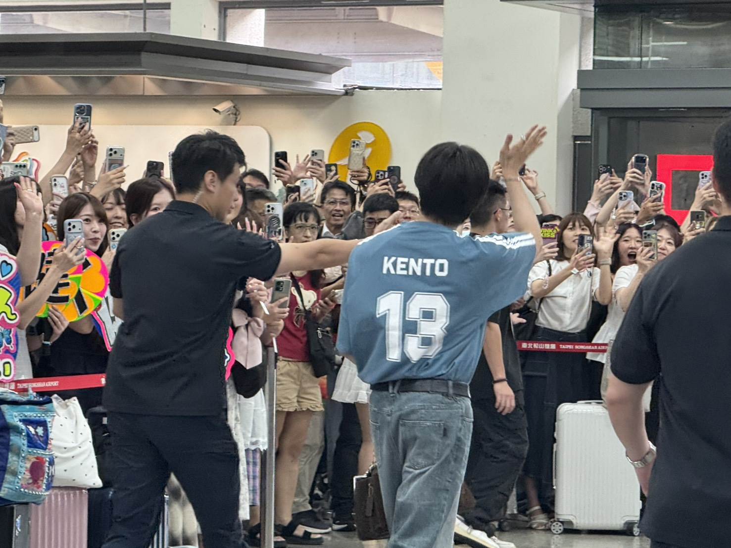 中島健人身穿背號13號寫著「Kento」的淺藍色球衣搭配牛仔褲現身機場，包上還掛著「青眼白龍」的小卡。（圖／記者楊雅芸攝）