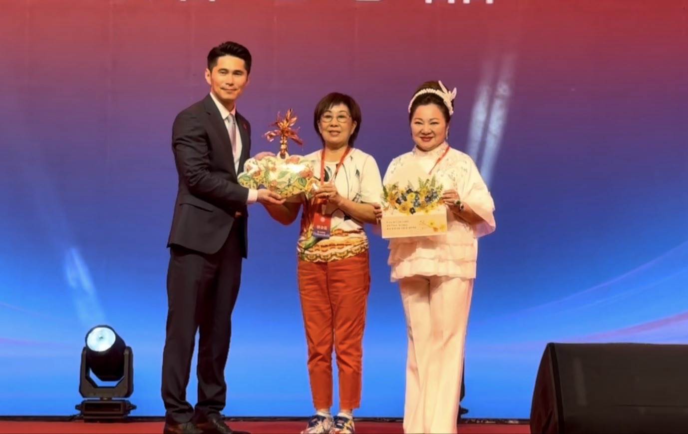 林金花（中）代表台灣好友團送上親製的作品給新任會長林世榮。（圖／長興影視提供）