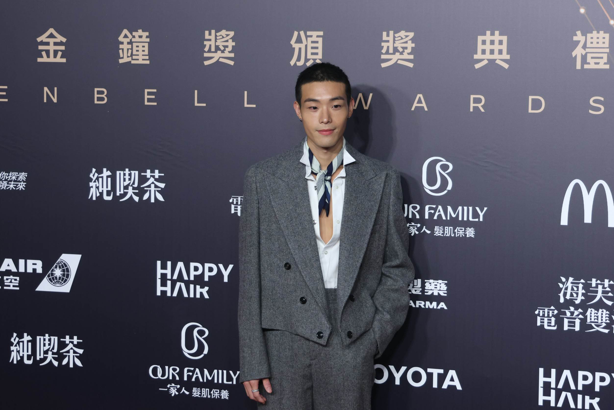牧森身穿灰色西裝，內搭襯衫刻意敞開至腹部上方，再配上藍白條紋短領帶，打破傳統正式西裝的拘謹感。（圖／東森娛樂）